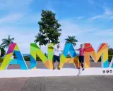 Two men pose with arms outstretched in front of a colorful "PANAMÁ" sign, suggesting Panama is gay friendly and a welcoming destination.