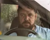 Russell Crowe bakom ratten i en bil, med regndroppar på vindrutan. En intensiv scen från filmer med Russell Crowe.
