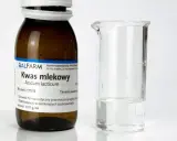 Butelka z napisem "Kwas mlekowy" i zlewka z płynem. Czy kwas mlekowy jest szkodliwy? Zależy od stężenia i zastosowania.