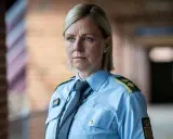 En kvinna i uniform från uniformen serie, med blå skjorta och slips, blickar ut.