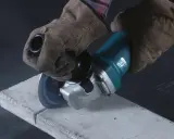 Manos enguantadas usan una radial para cortar hormigón. La radial es una herramienta eléctrica versátil para cortar y desbastar.