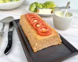Un pain de thon savoureux, garni de rondelles de tomate fraîche, prêt à être dégusté avec une salade verte et une sauce crémeuse.