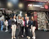 Grupa osób na targach poligraficznych, pozuje przed maszyną drukarską Comexi F1.