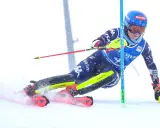 Narciarka alpejska w akcji, walcząca o jak najlepszą klasyfikację. Dynamiczny skręt, śnieg wzbijający się spod nart.