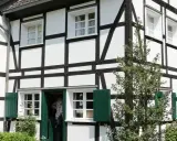 Ein liebevoll saniertes Fachwerkhaus mit grünen Fensterläden und üppiger Bepflanzung.