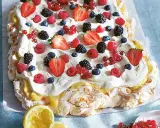 En stor pavlova med grädde och färska bär, perfekt för påskfirandet.