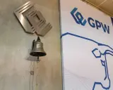 Dzwonek giełdowy GPW, symbolizujący rozpoczęcie obrotu, obok logo giełdy.