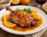 Pechuga de pato a la naranja, glaseada y dorada, servida con rodajas de naranja fresca y romero.