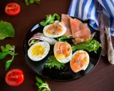 Jajka na twardo z łososiem i sałatą, idealne na dietę low carb. Pomidorki i zielenina dopełniają danie.