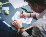 UX designer szkicuje interfejs aplikacji na papierze.