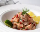 Un classique tartare de saumon, frais et coloré, garni d'aneth, de baies roses et servi avec des quartiers de citron vert et de citron jaune.