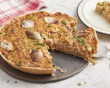 Une délicieuse tarte à l'oignon, garnie d'oignons caramélisés et de ciboulette fraîche, est prête à être dégustée. Une part est servie sur une assiette.