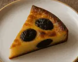 Tranche de far breton, un gâteau moelleux aux pruneaux, sur une assiette blanche.