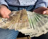 Ręce trzymające stos banknotów 100 zł i 200 zł. Ile razy można dać darowiznę dziecku? Tyle, ile masz środków.