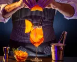 Barman prepara un Aperol Spritz, mostrando los distintos tipos de aperol y sus guarniciones.