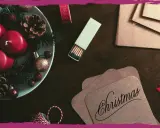 Candele rosse, pigne e decorazioni natalizie su un tavolo scuro, pronte per scrivere una poesia di Natale per adulti.