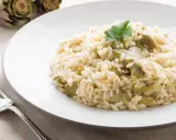 Un cremoso risotto con carciofi freschi, guarnito con un ciuffo di prezzemolo, pronto per essere gustato.