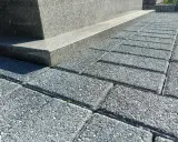 Szare kostki brukowe tworzą ścieżkę wokół pomnika. Idealne, by położyć wokół pomnika, tworząc schludne i trwałe otoczenie.
