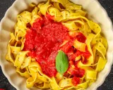 Pappardelle z sosem pomidorowym i bazylią, klasyczne makaron po włosku, podane w kremowej misce.