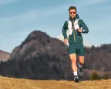 Ein Mann läuft in den Bergen, was ist ein ultramarathon? Er trägt Laufkleidung und eine Weste.