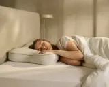 Junge Frau schläft tief und fest auf einem ergonomischen Kissen. Ein schnelles Hausmittel zum Einschlafen, das für erholsamen Schlaf sorgt.