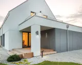 Nowoczesne oświetlenie elewacji podkreśla architekturę domu. Lampy ścienne i stojące tworzą przytulną atmosferę.