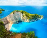 Widok na Navagio Beach, jedną z najpiękniejszych greckich atrakcji. Białe klify, turkusowa woda i zielona roślinność tworzą rajski krajobraz.