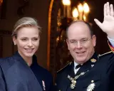 Charlene, furstinna av Monaco, ler vid sidan av prins Albert. Han vinkar glatt till publiken.