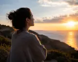 Frau blickt nachdenklich auf Sonnenuntergang über dem Meer. Die Weite spiegelt ihre **Angst vor Kontrollverlust** wider, während sie nach innerem Frieden sucht.