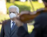 Un uomo con mascherina bianca ascolta un violinista. Un bel tacer non fu mai scritto, ma la musica parla.
