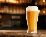 Schłodzony pilsner z obfitą pianką na blacie drewnianego baru.