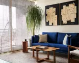 Salones muy pequeños con encanto: sofá azul vibrante, mesa de centro de madera, planta frondosa y arte abstracto en las paredes.