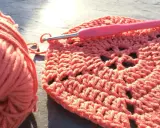 Koralowa włóczka i szydełko tworzą wzór. Powstaje piękny, ażurowy crochet pattern.
