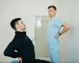 Fizjoterapeuta pomaga pacjentowi z chorobą Scheuermana w ćwiczeniach poprawiających postawę.