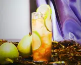 En uppfriskande drink med päron och lime, perfekt för svenska drinkar. Guldfärgad konfetti och lila tyg skapar festlig stämning.