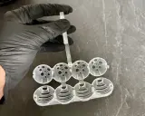 Hand in black glove holds a mold for making klostein selber machen. The mold has eight spherical compartments.