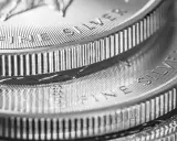 Zbliżenie na stos monet z napisem "FINE SILVER". Błyszczące srebro, idealne na prognozy inwestycyjne.