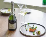 Flasche Charles Heidsieck Champagner neben Lachs mit Kaviar auf einem Teller.