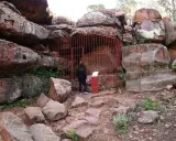 Persona observa pinturas rupestres albarracín, protegidas por una valla roja.