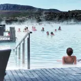 Relaks w Blue Lagoon, geotermalnym basenie z parą unoszącą się nad turkusową wodą. Ludzie kąpią się i odpoczywają.