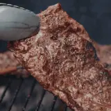 Soczysty stek na ruszcie, idealny do grillowania. Aromatyczny zapach unosi się w powietrzu, zapowiadając pyszną ucztę.
