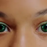 Oczy z zielonymi soczewkami, które przyciągają wzrok na tle naturalnej, brązowej oprawy.