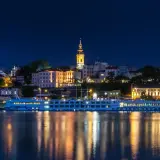 Nocny Belgrad z rzeką i statkiem wycieczkowym. Czy do Serbii potrzebny jest paszport? Sprawdź przed podróżą!