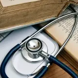 Libri antichi e uno stetoscopio su una tastiera, evocano lo studio della medicina legale.