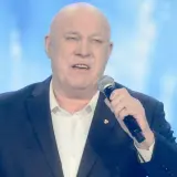 Ryszard Rynkowski, znany artysta, śpiewa do mikrofonu. Jego wiek nie przeszkadza mu w karierze.