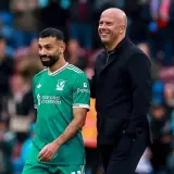 Piłkarz Liverpoolu w zielonej koszulce i łysy mężczyzna w czarnej kurtce uśmiechają się. To może być moment po udanych transferach Liverpoolu.