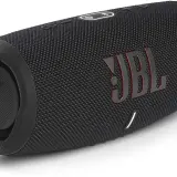 Czarny głośnik JBL z czerwonym logo. Dowiedz się, jak podłączyć słuchawki JBL do telefonu, by cieszyć się muzyką.