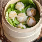 Délicieux ravioli crevette italien, cuits à la vapeur dans un panier en bambou, servis sur des feuilles de laitue.
