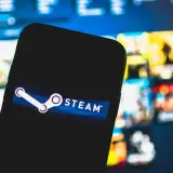 Smartfon z logo Steam na tle gier. Chcesz wiedzieć, jak wyłączyć Big Picture Steam?