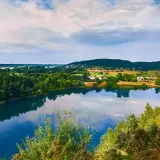 Malownicze jezioro turkusowe na Wolinie, otoczone zielonymi lasami i niewielką wsią.